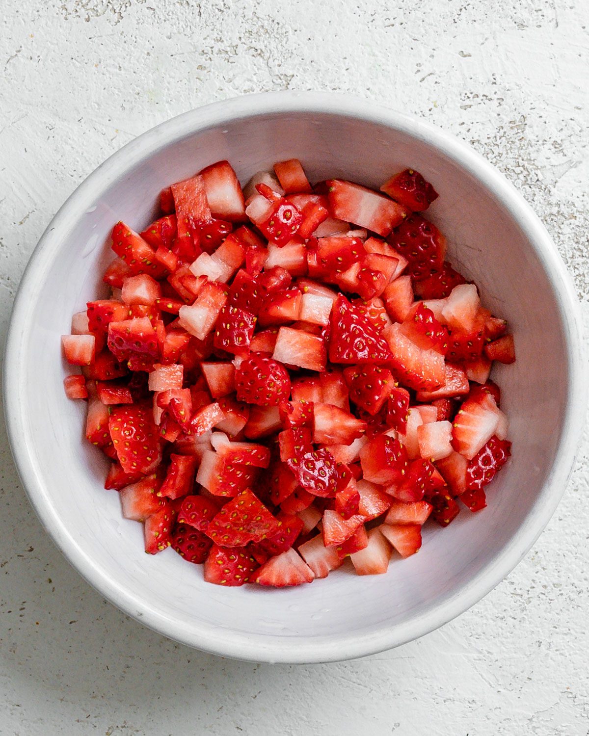 diced strawberries in a bowl against a white surface
