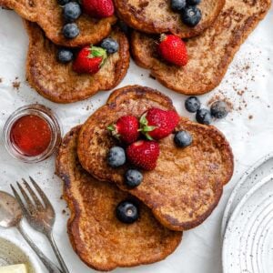 several completed just egg french toast with berries on top against a white surface