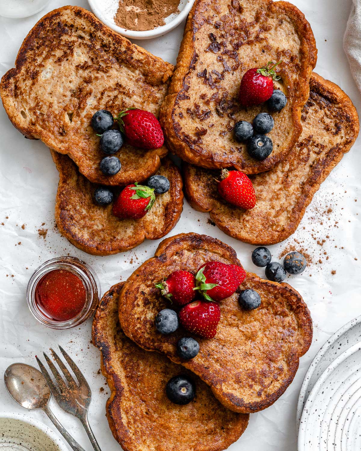 several completed just egg french toast with berries on top against a white surface