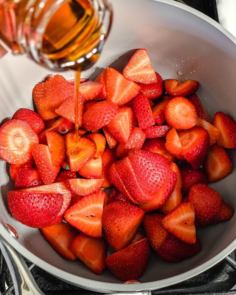 process shot of adding vanilla extract to bowl of strawberries