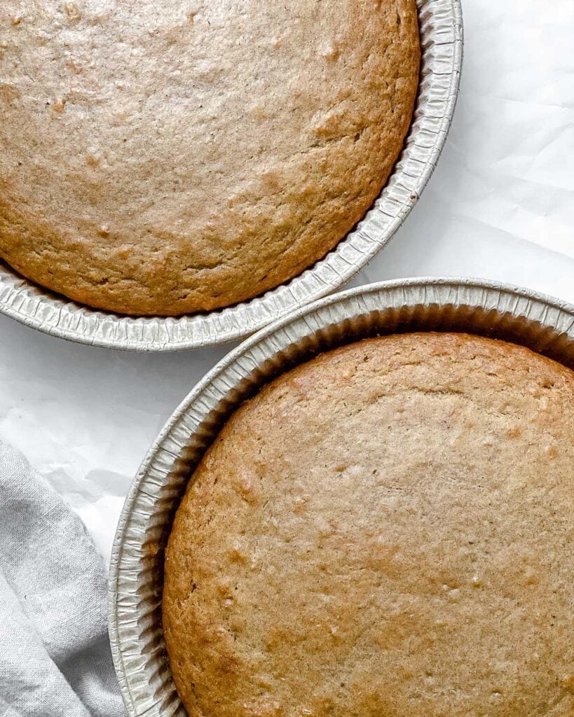 two post baked vanilla cakes in separate containers against a white background
