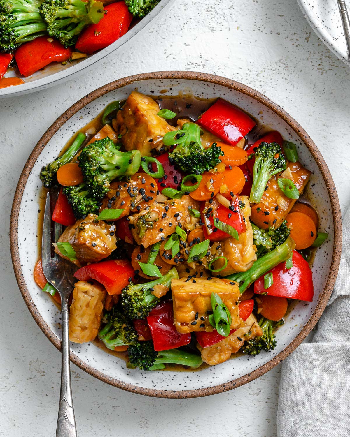completed Easy Tempeh Stir-Fry plated on a white plate against a white surface
