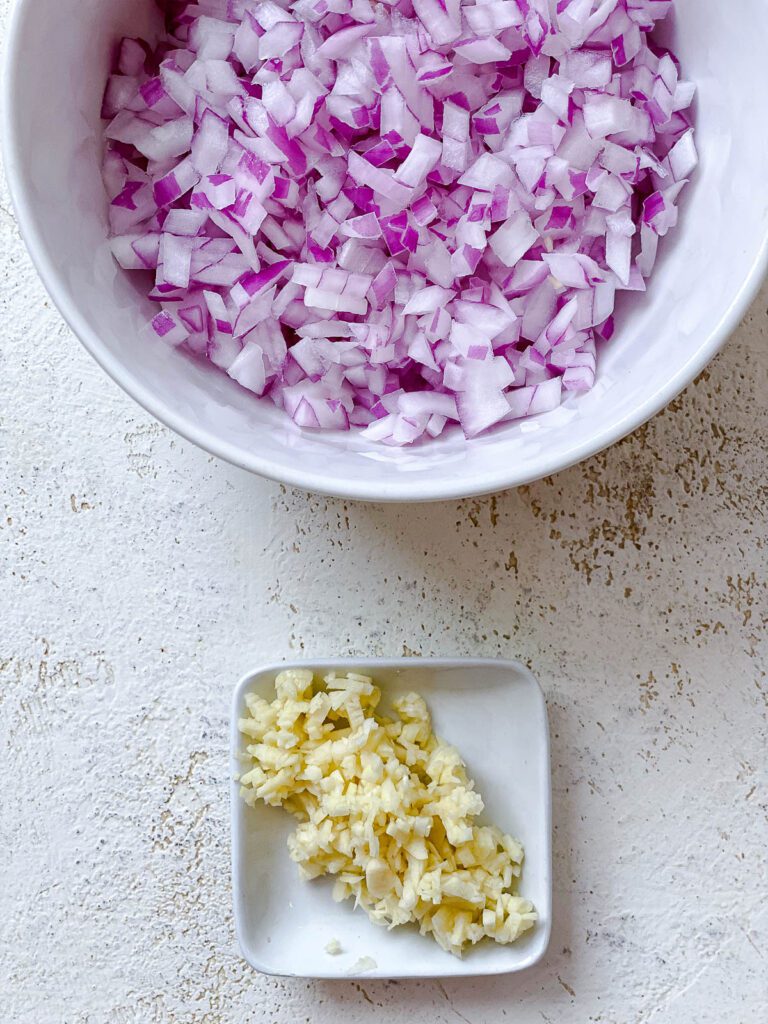 bowl of onion and minced garlic on a white surface