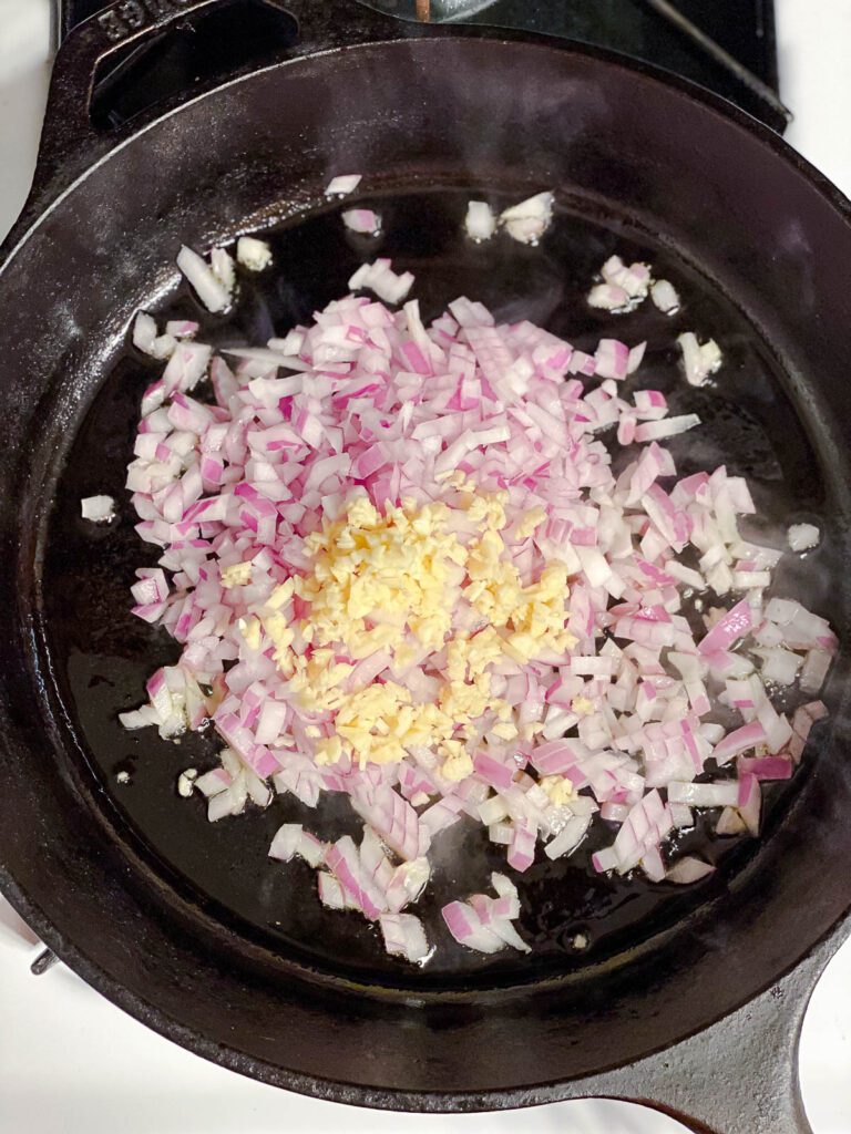 process shot of cooking oil, onions, and garlic in bowl