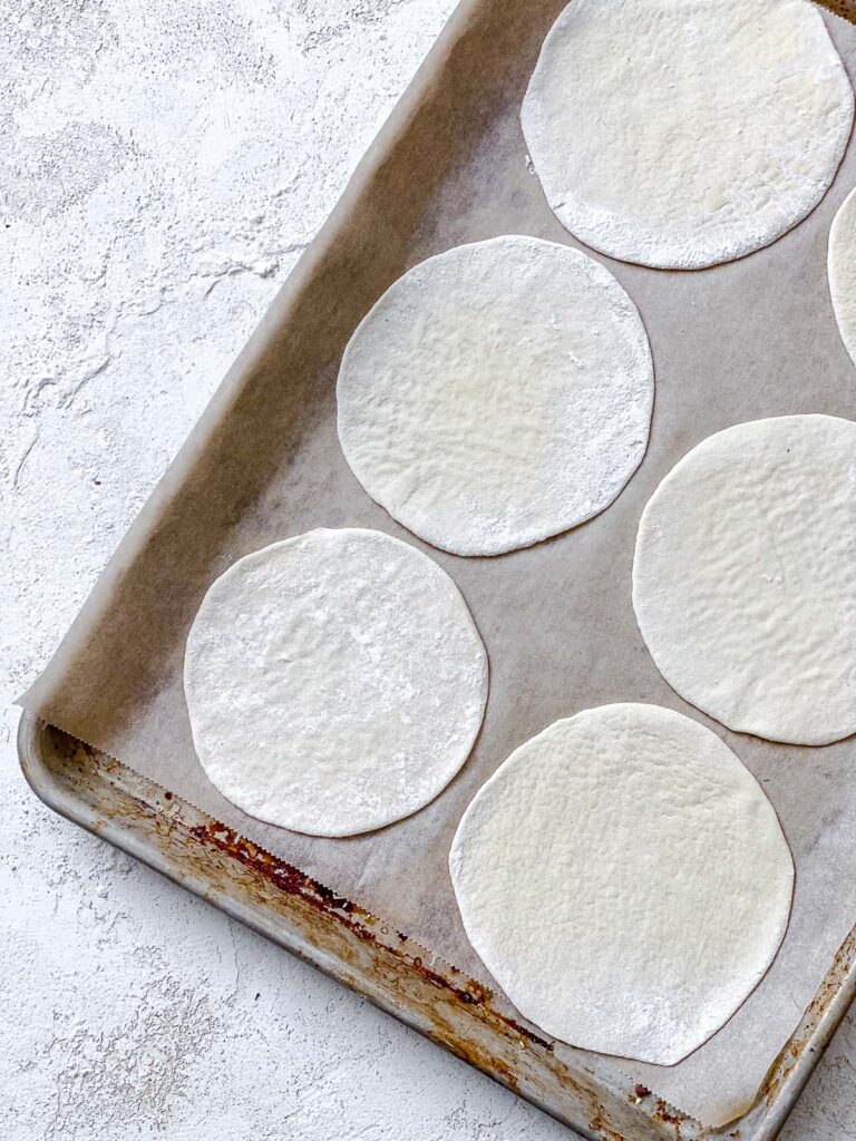 several flattened balls of dough on baking sheet