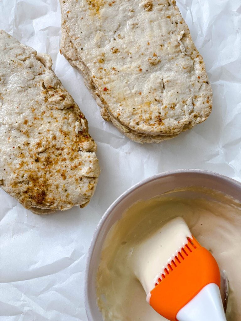 two Vegan Cordon Bleu sandwiches alongside bowl of coating