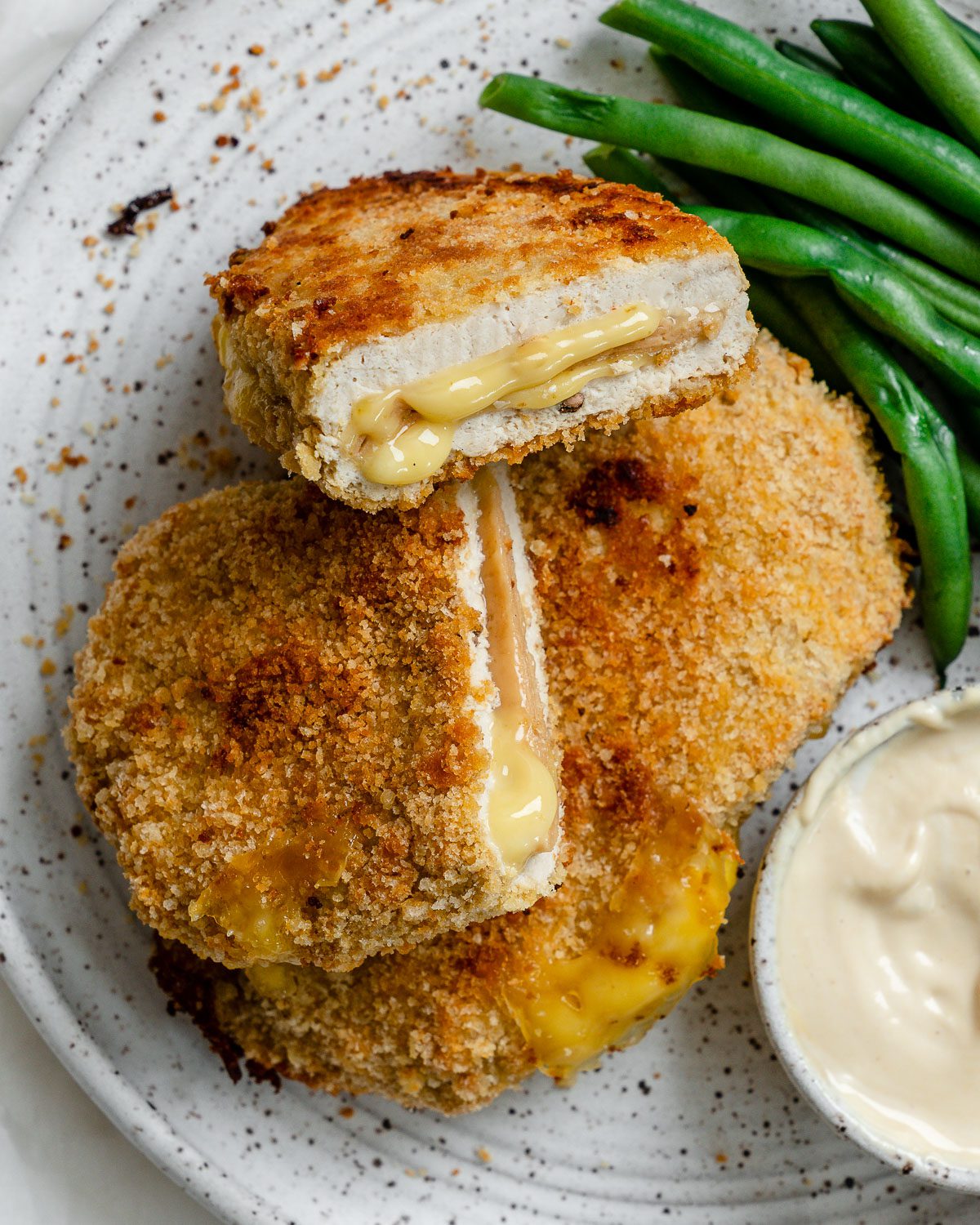 completed Vegan Cordon Bleu plated with green beans and sauce on the side