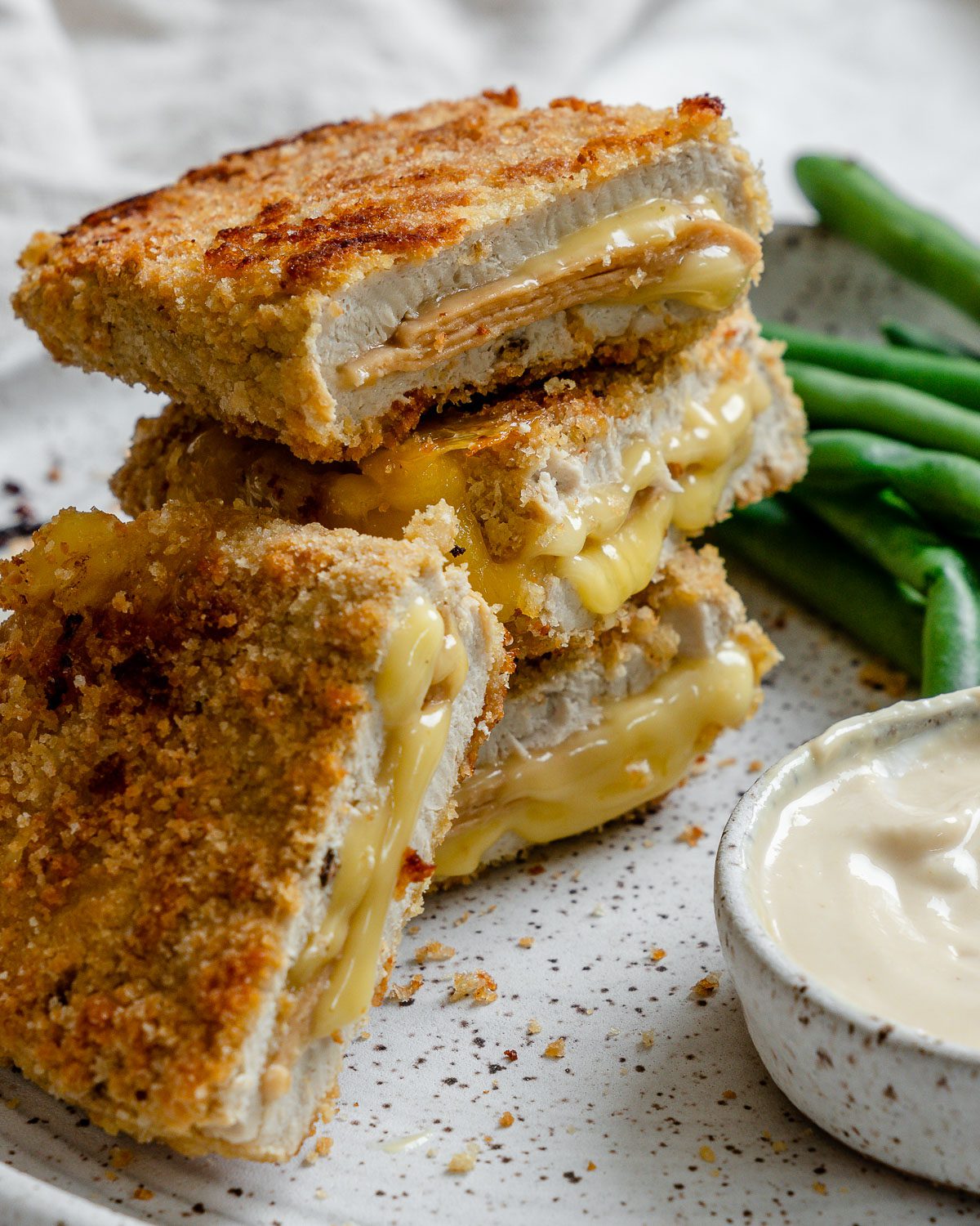 completed Vegan Cordon Bleu plated with green beans and sauce on the side