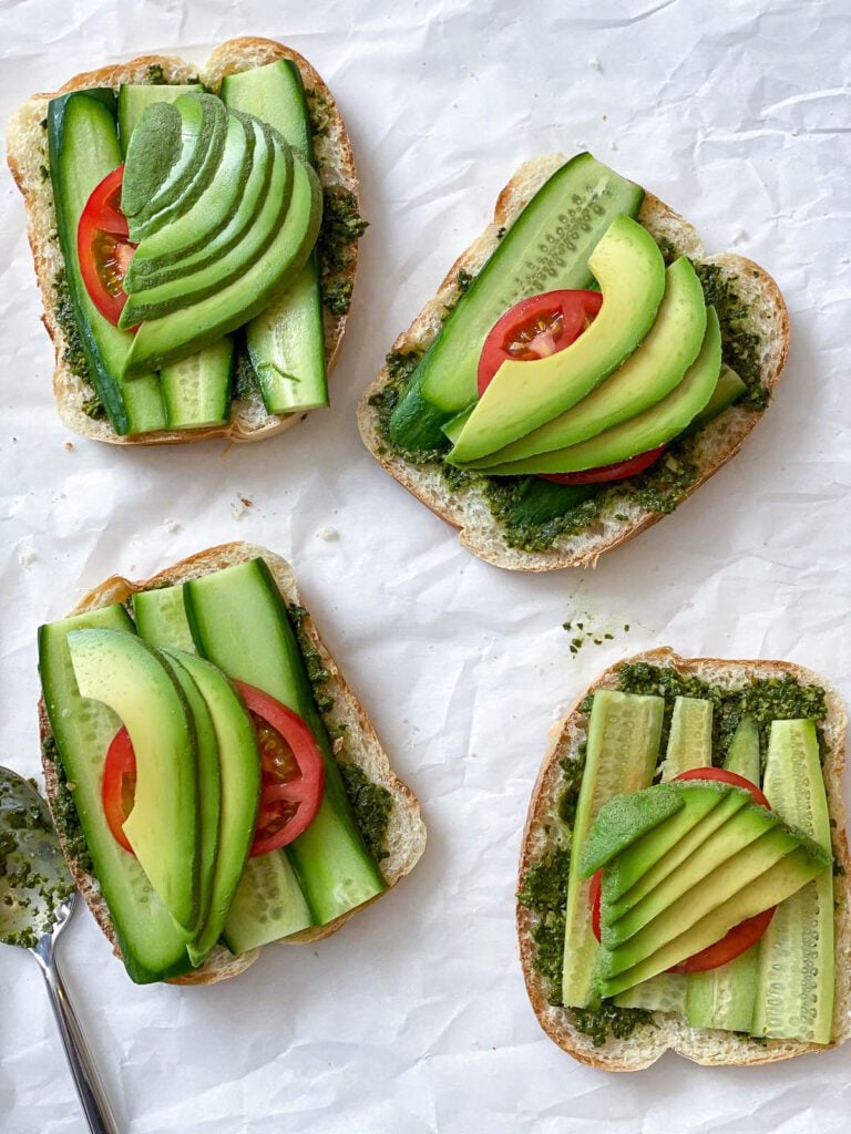 process shot showing addition of cucumber, avocado, and tomatoes on bread