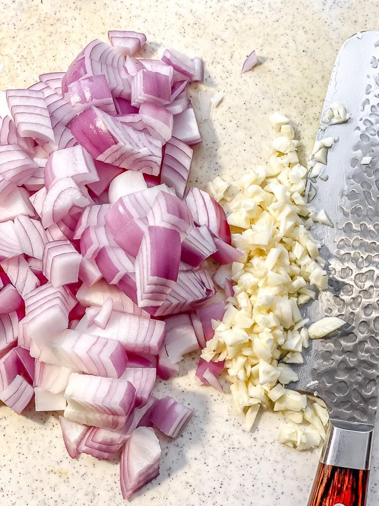 process shot showing diced onions and garlic on cutting board