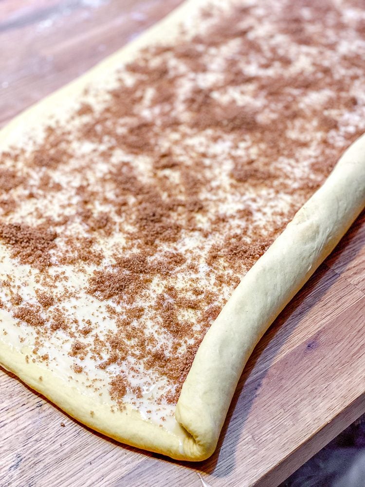 process shot showing cinnamon mixture added to dough