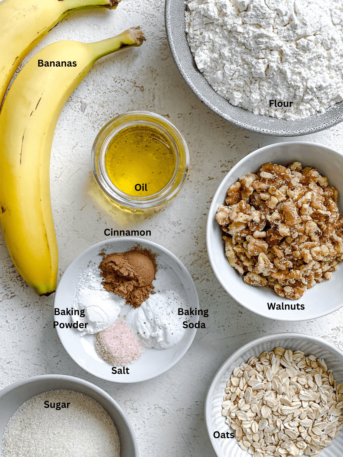 ingredients for Vegan Banana Oatmeal Muffins measured out on a white surface
