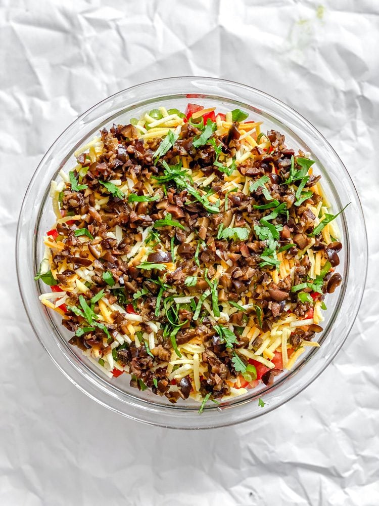 process shot showing ingredients for Vegan 7 Layer Dip (Quick and Easy) added to bowl