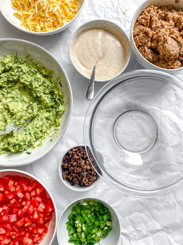 process shot showing ingredients for Vegan 7 Layer Dip (Quick and Easy) added to bowl