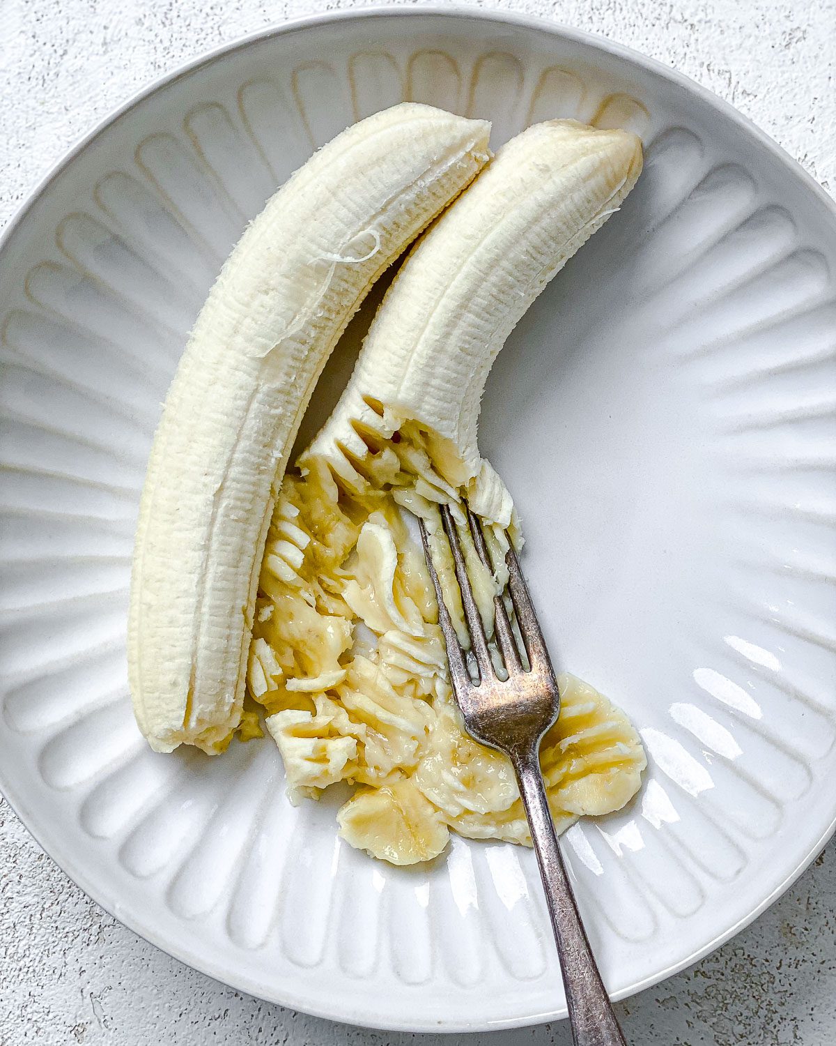 process shot showing mashing bananas in a bowl