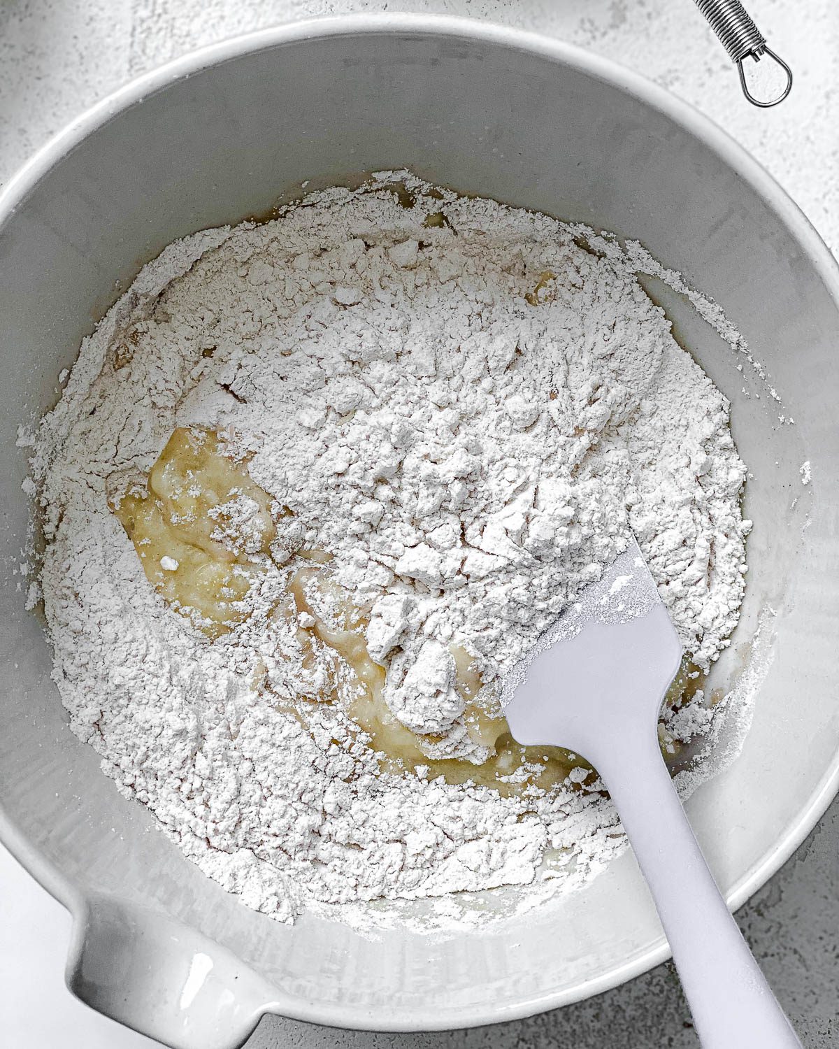 process shot showing mixing dry ingredients into bowl of bananas