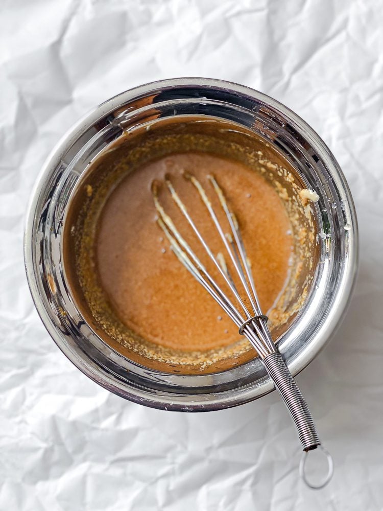 Process shot showing stirring dressing ingredients in a bowl.