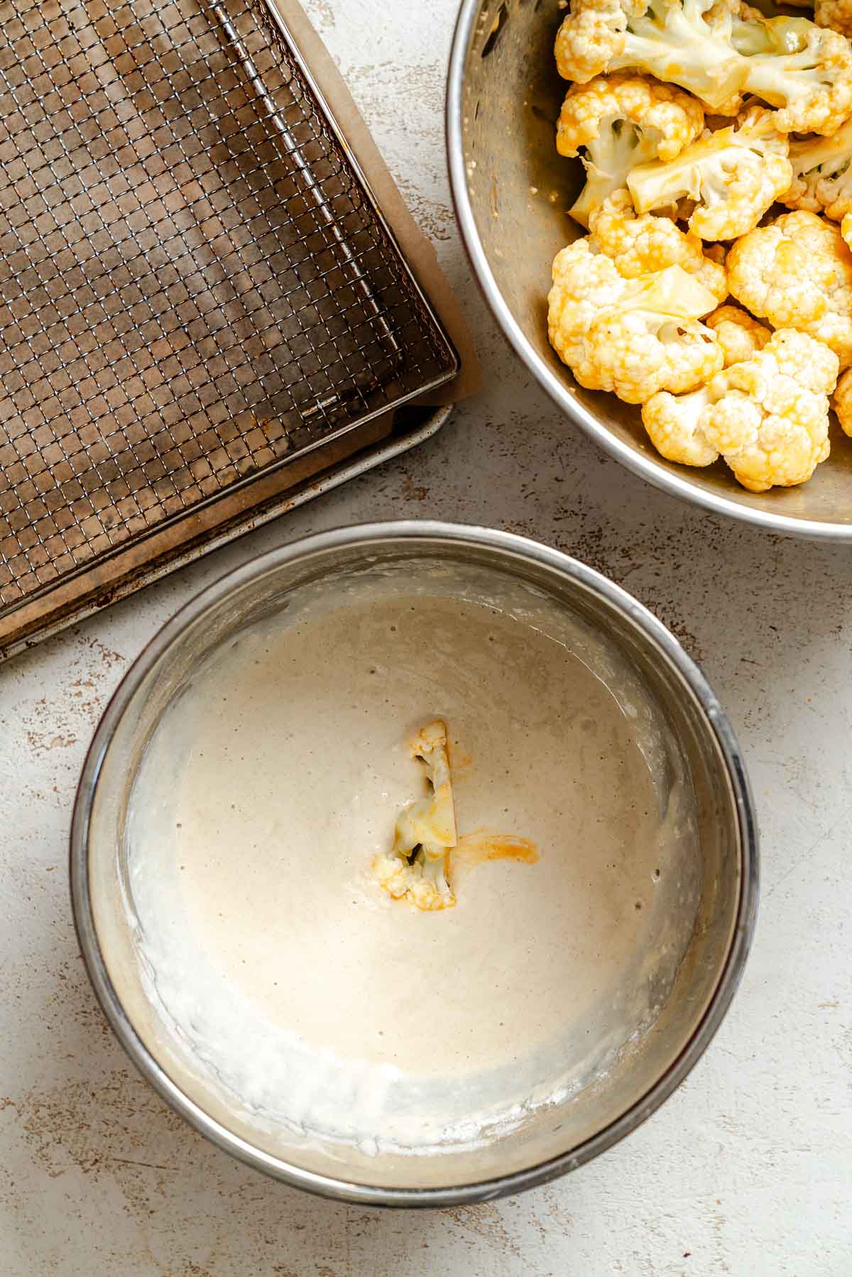 Process shot showing adding cauliflower to bowl of batter.