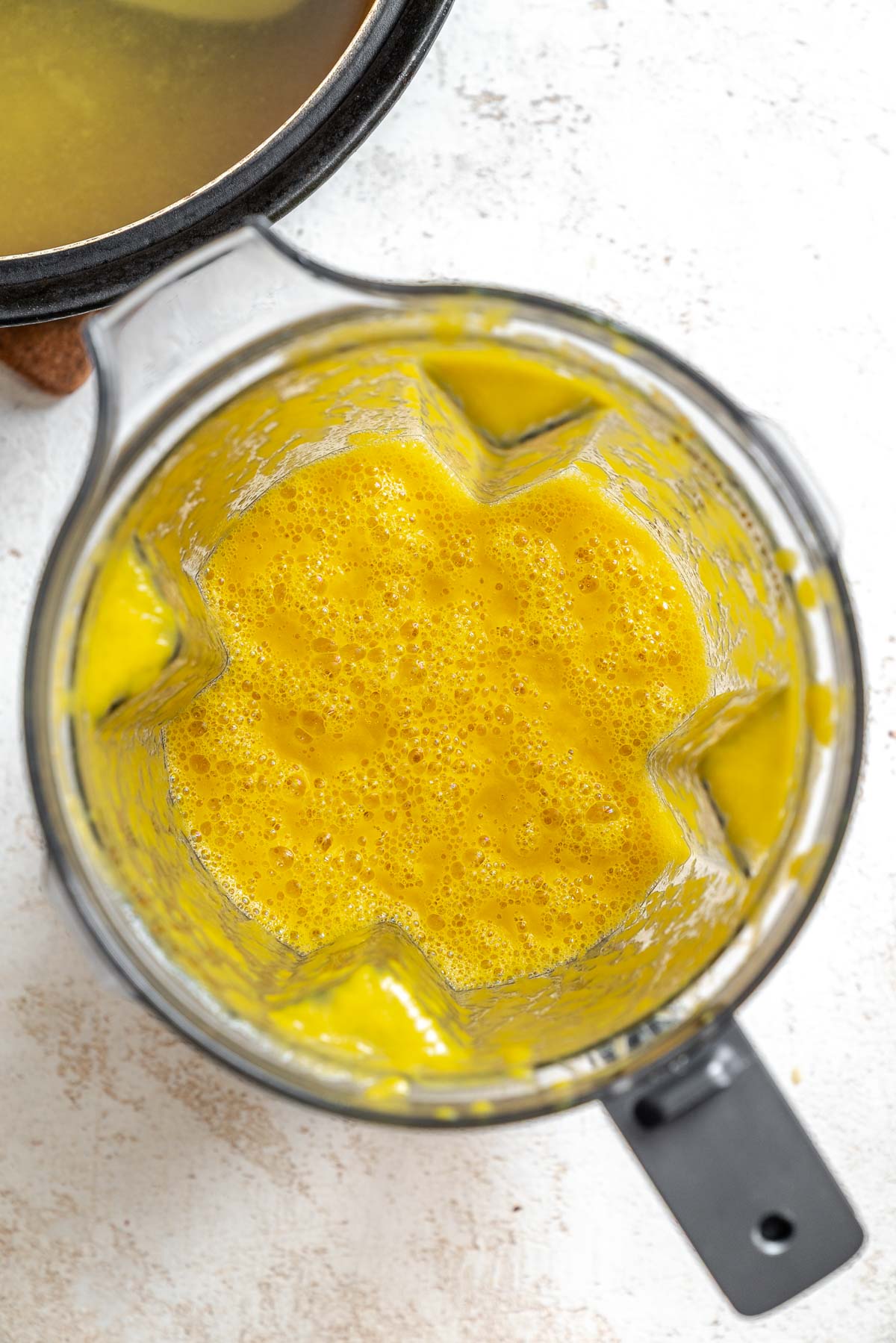 Process shot showing veggies blended in a blender.