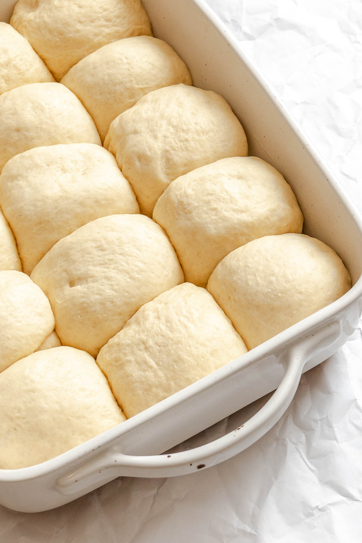Process shot showing balls of dough in baking dish.