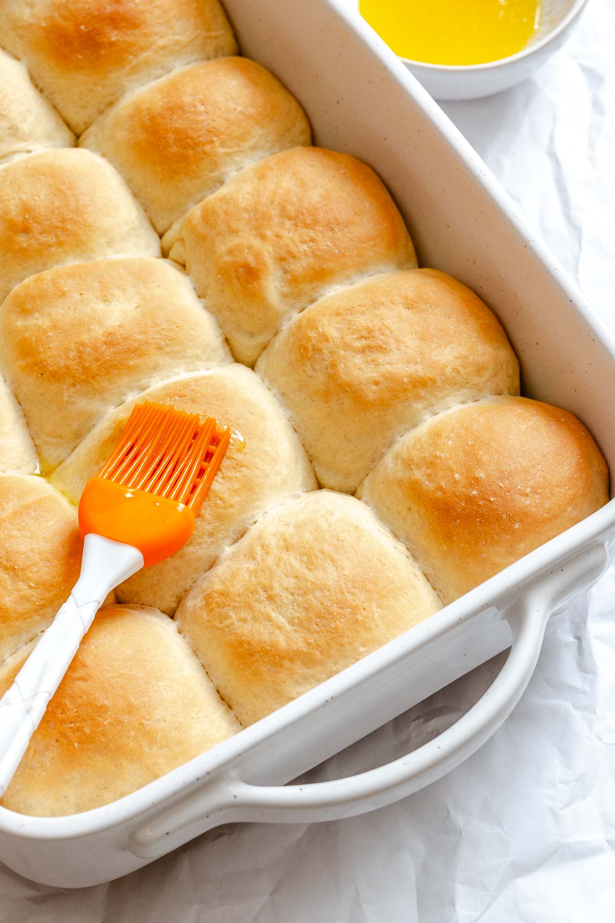 Process shot showing brushing vegan butter mixture on rolls.