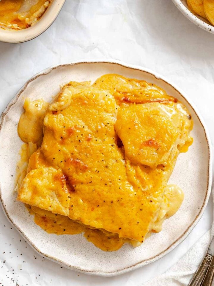 Completed Vegan Scalloped Potatoes on a plate on a white surface.