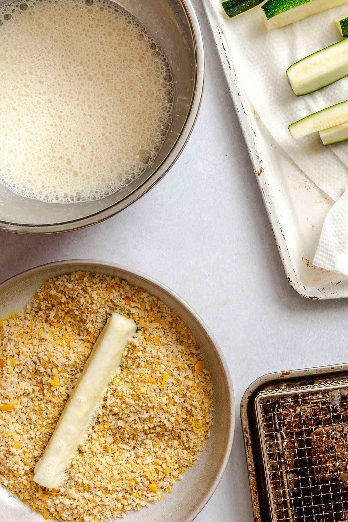 Process shot showing adding zucchini fry to panko mixture.