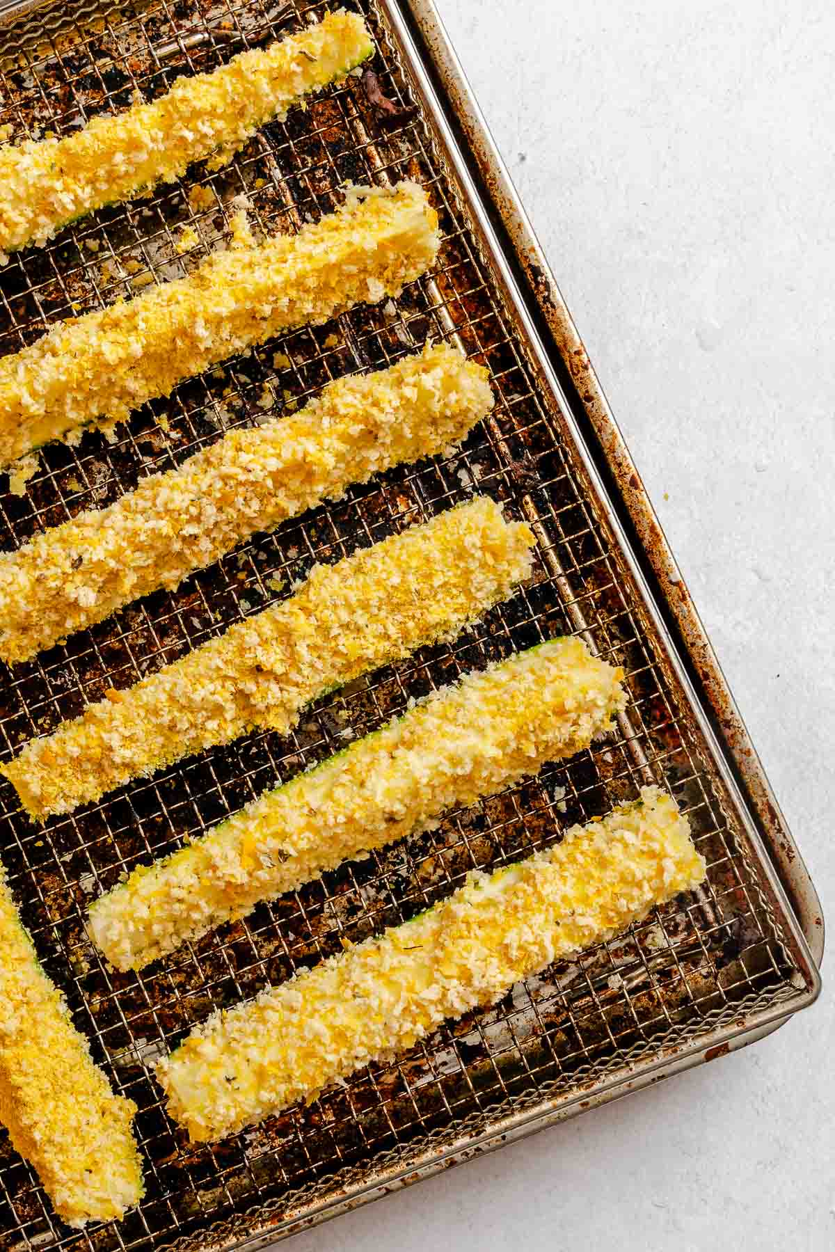 Process shot showing zucchini fries added to air fryer.