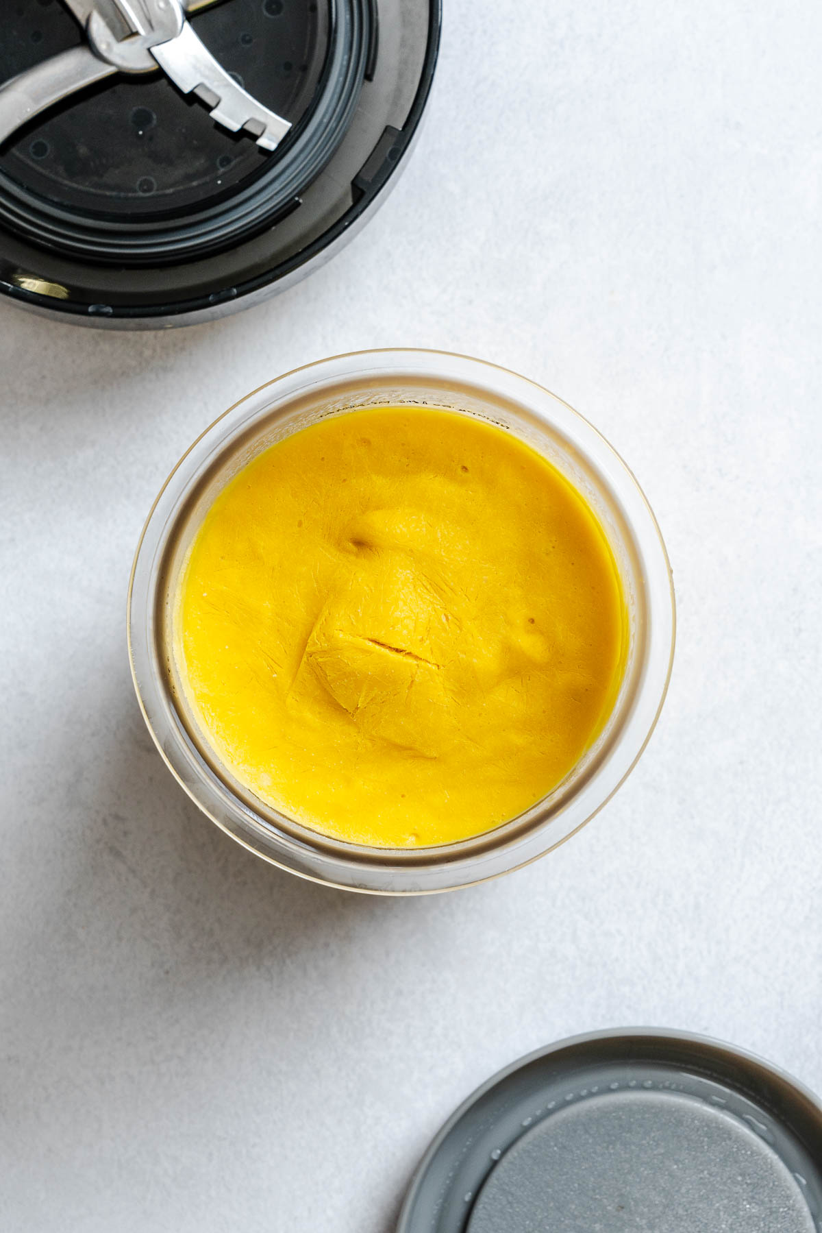 Process shot showing ingredients for Vegan Mango Ice Cream (Ninja Creami) in ninja creami container.