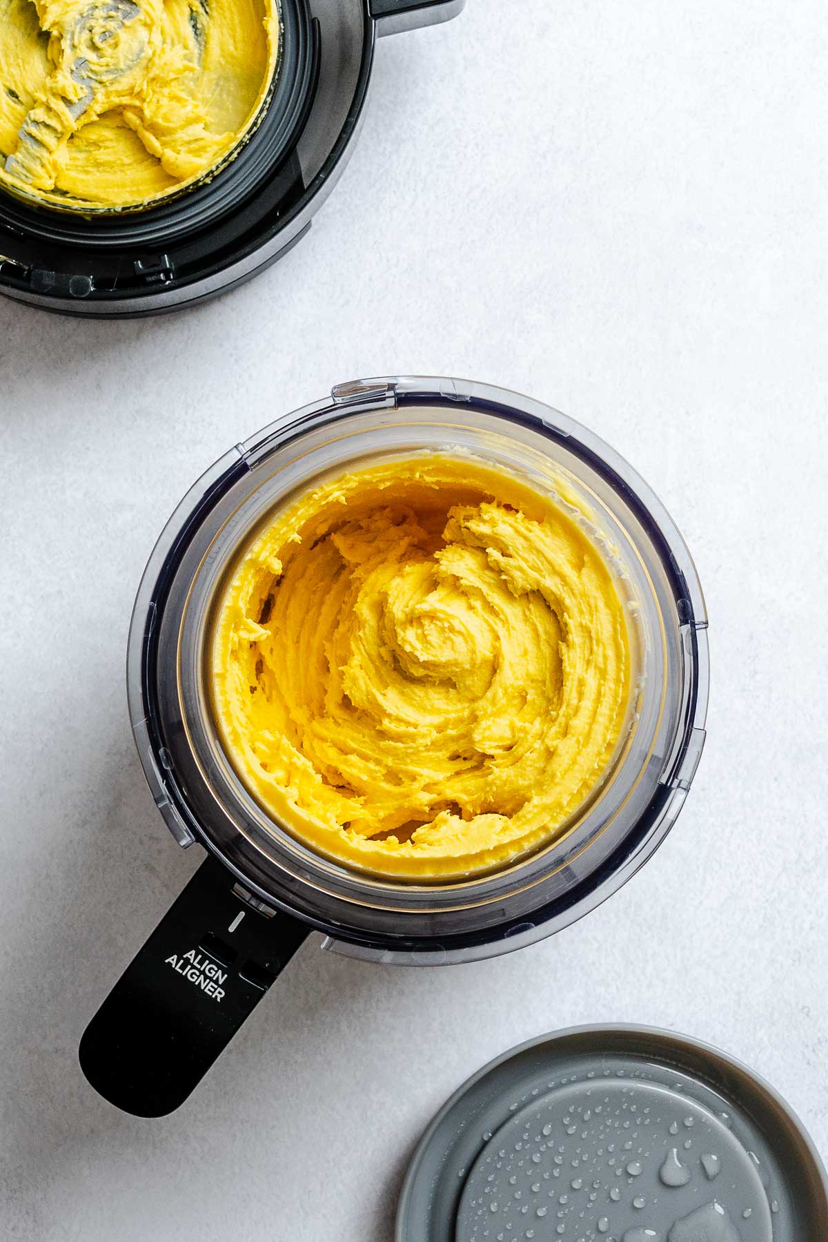 Process shot showing ingredients for Vegan Mango Ice Cream (Ninja Creami) in ninja creami machine.