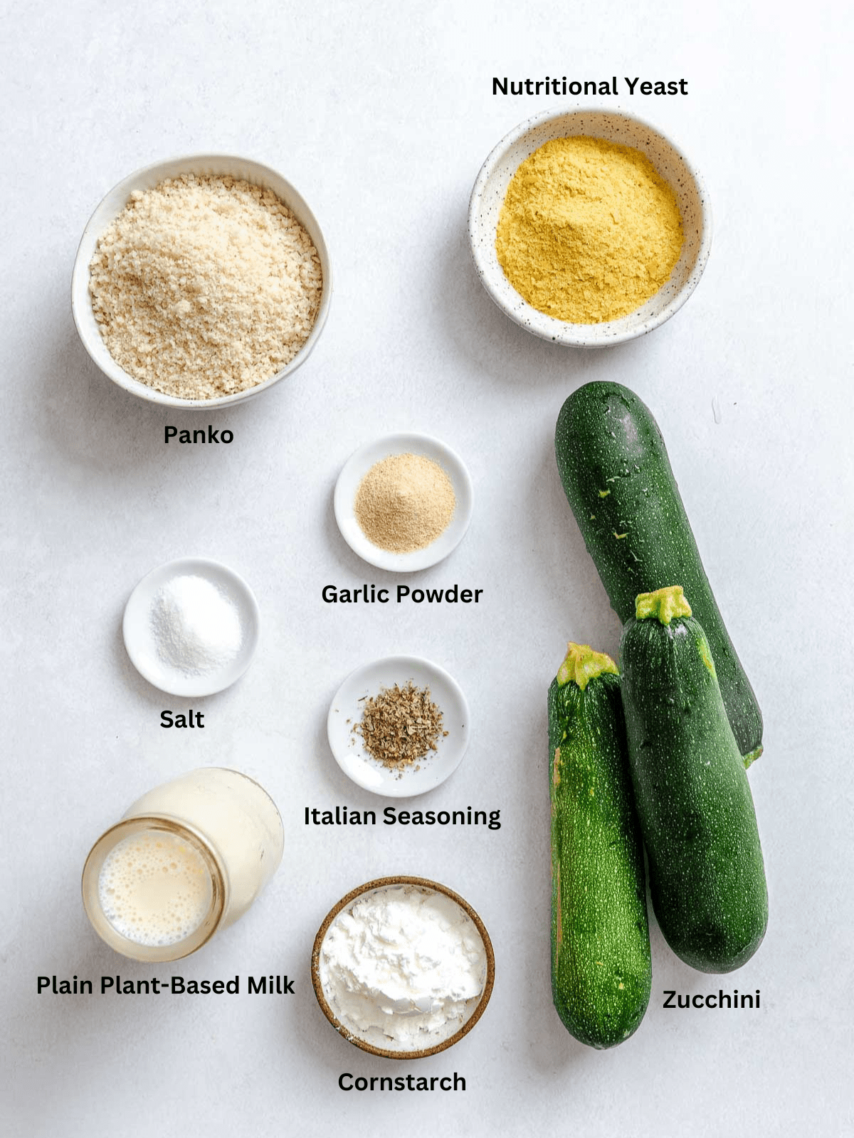 Ingredients for Air Fryer Zucchini Fries measured out on a white surface.