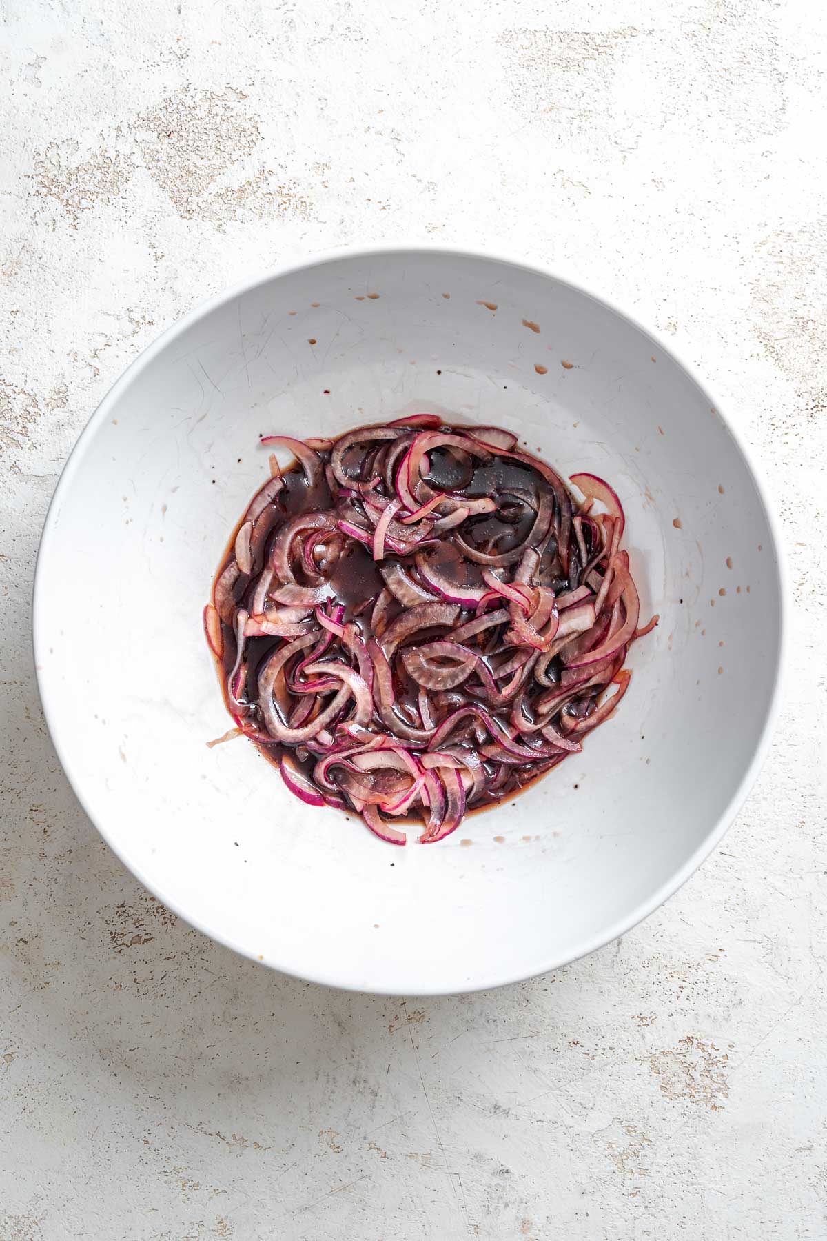 Process shot showing red onion mixture in a bowl.