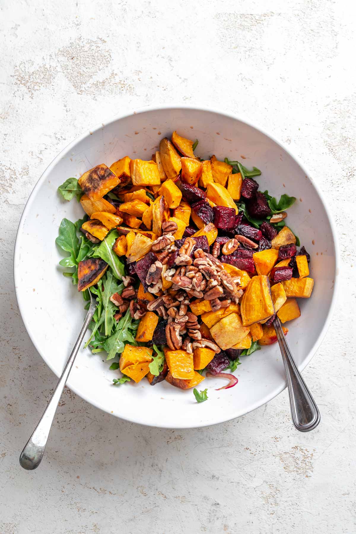 Process shot showing adding beets and sweet potato to bowl.