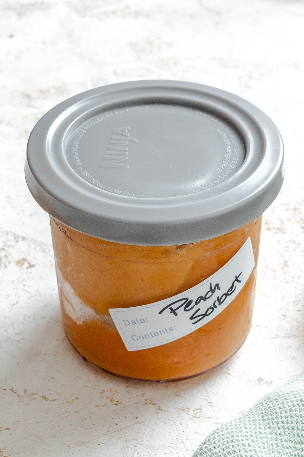 Completed Ninja Creami Peach Sorbet (Fresh or Canned) in a storage container.
