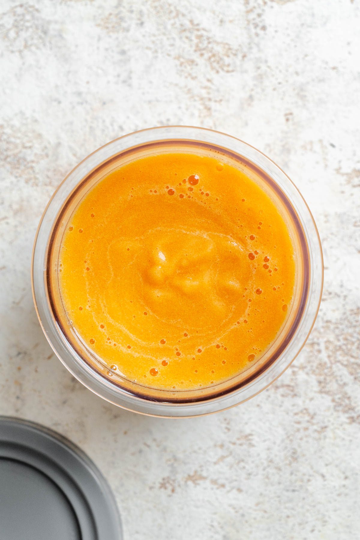 Process shot showing peach sorbet ingredients added to container.