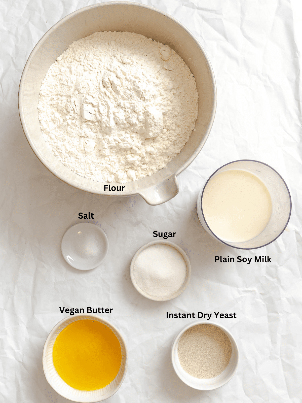 Ingredients for Fluffy Vegan Dinner Rolls measured out on a white surface.