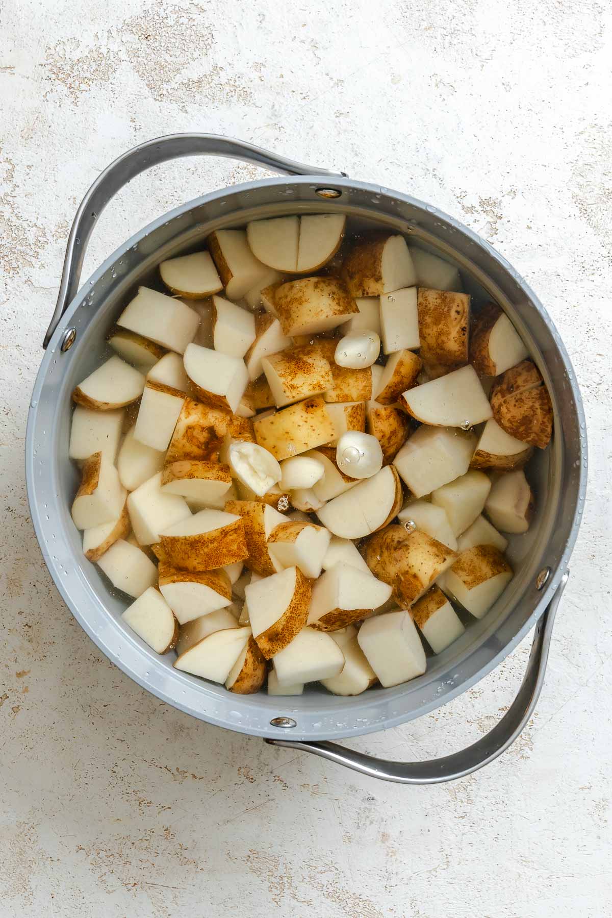 Process shot showing potatoes added to pot.