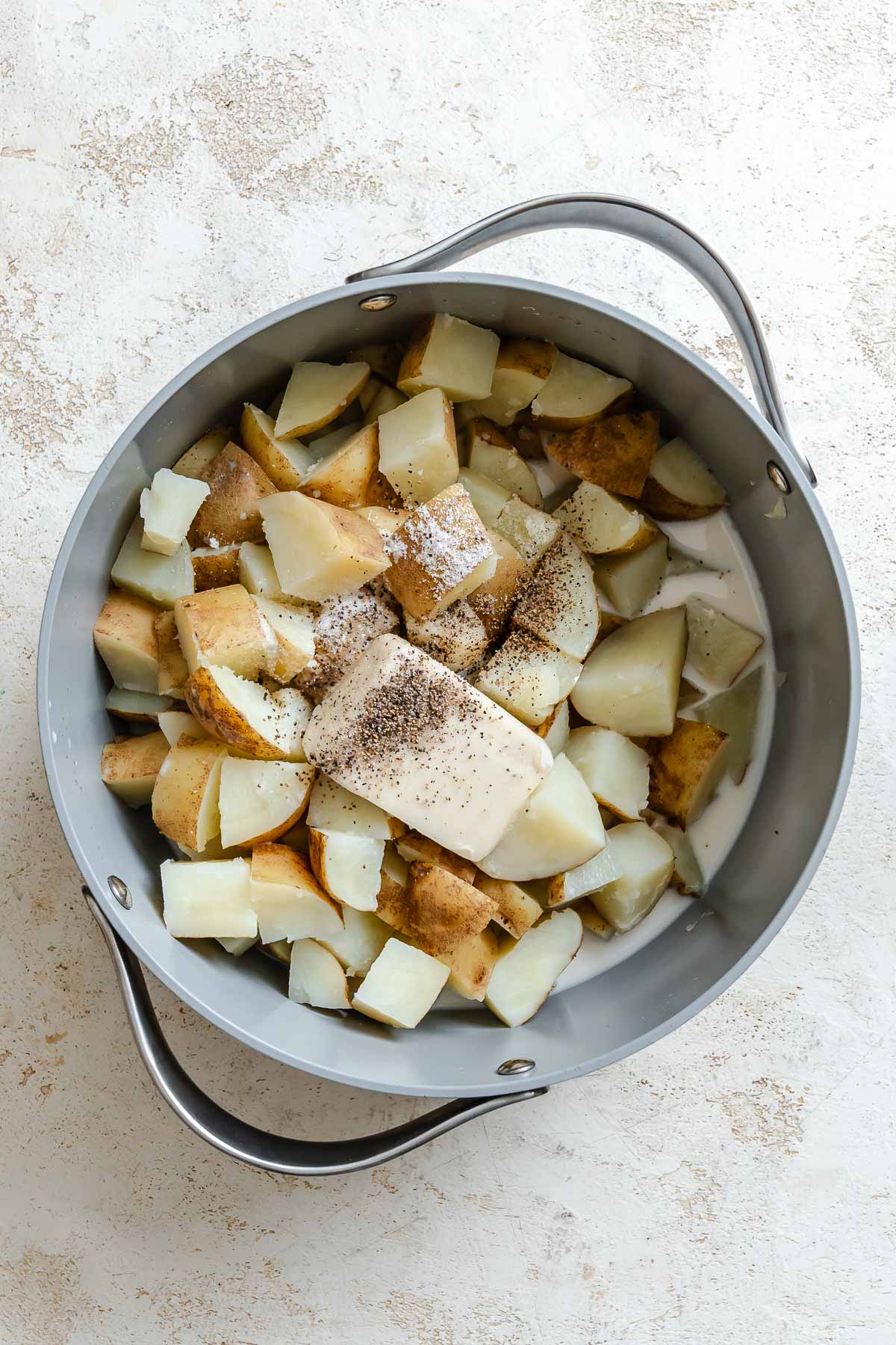 Process shot showing potatoes cooking in pot.