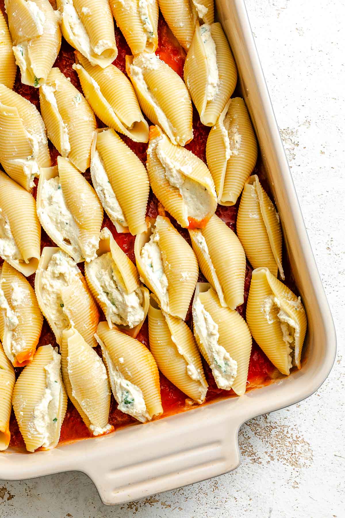 Process shot showing stuffed shells added to baking pan.