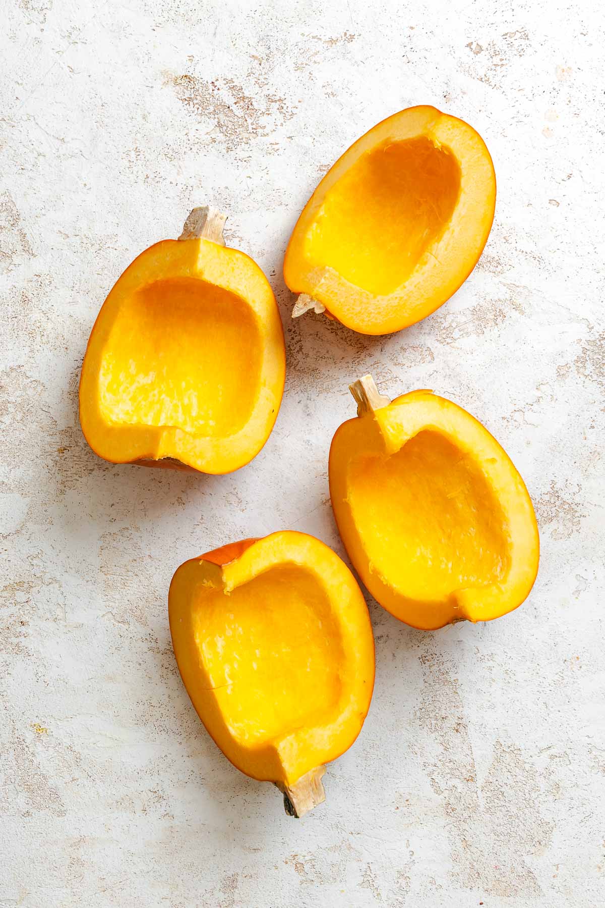 Process shots showing cut up pumpkin on white surface.