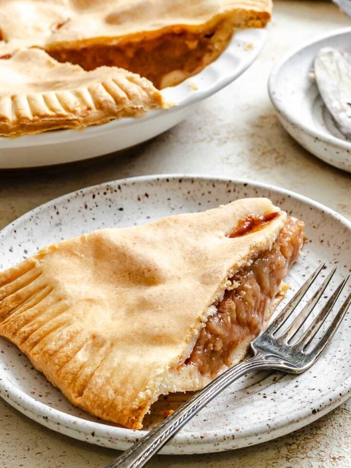 Completed Easy Vegan Apple Pie on a white surface and a slice on a plate.