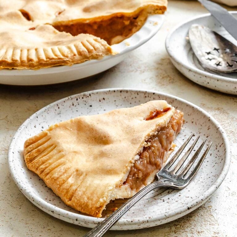 Completed Easy Vegan Apple Pie on a white surface and a slice on a plate.