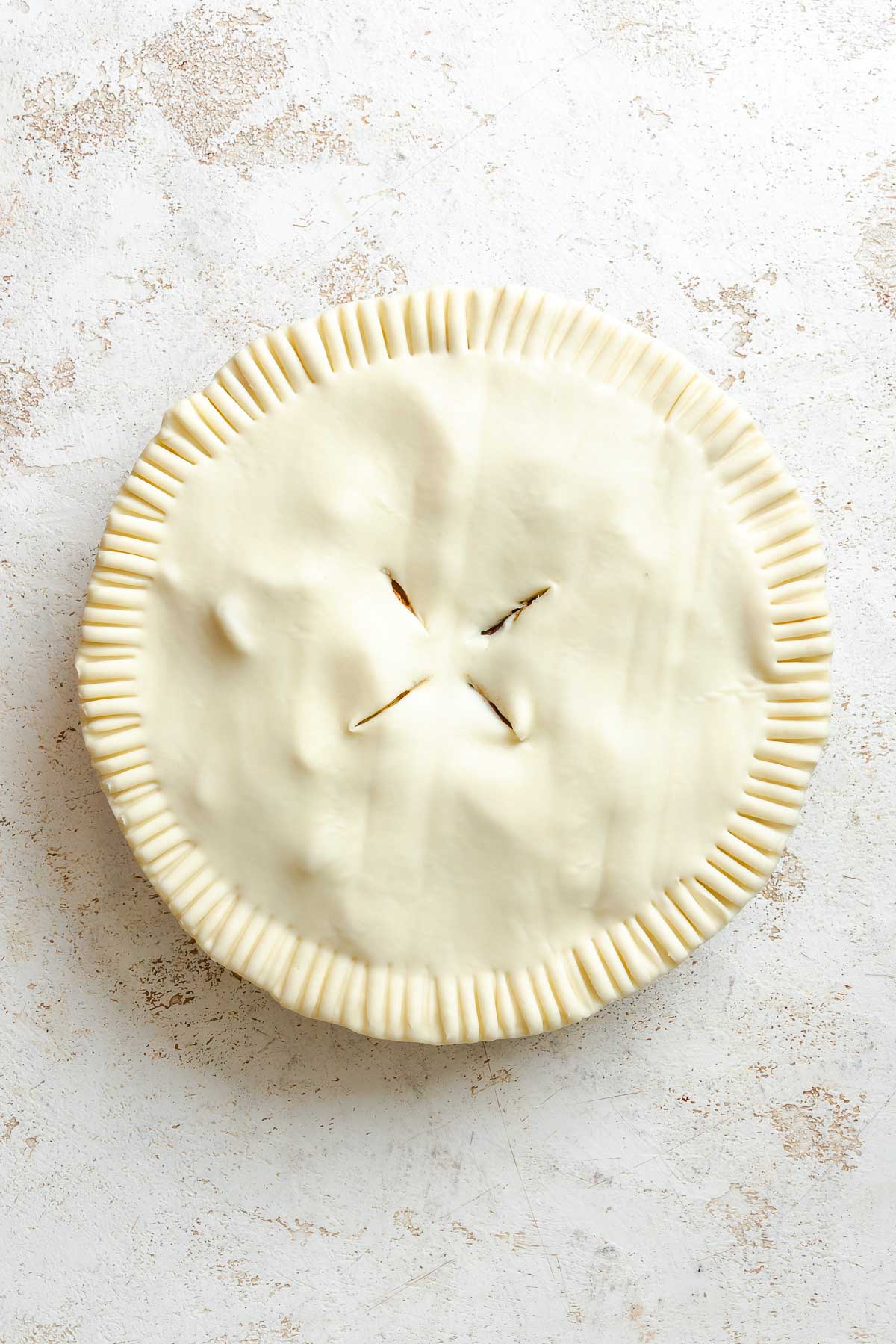Process shot showing the crust added to the top of the pie.
