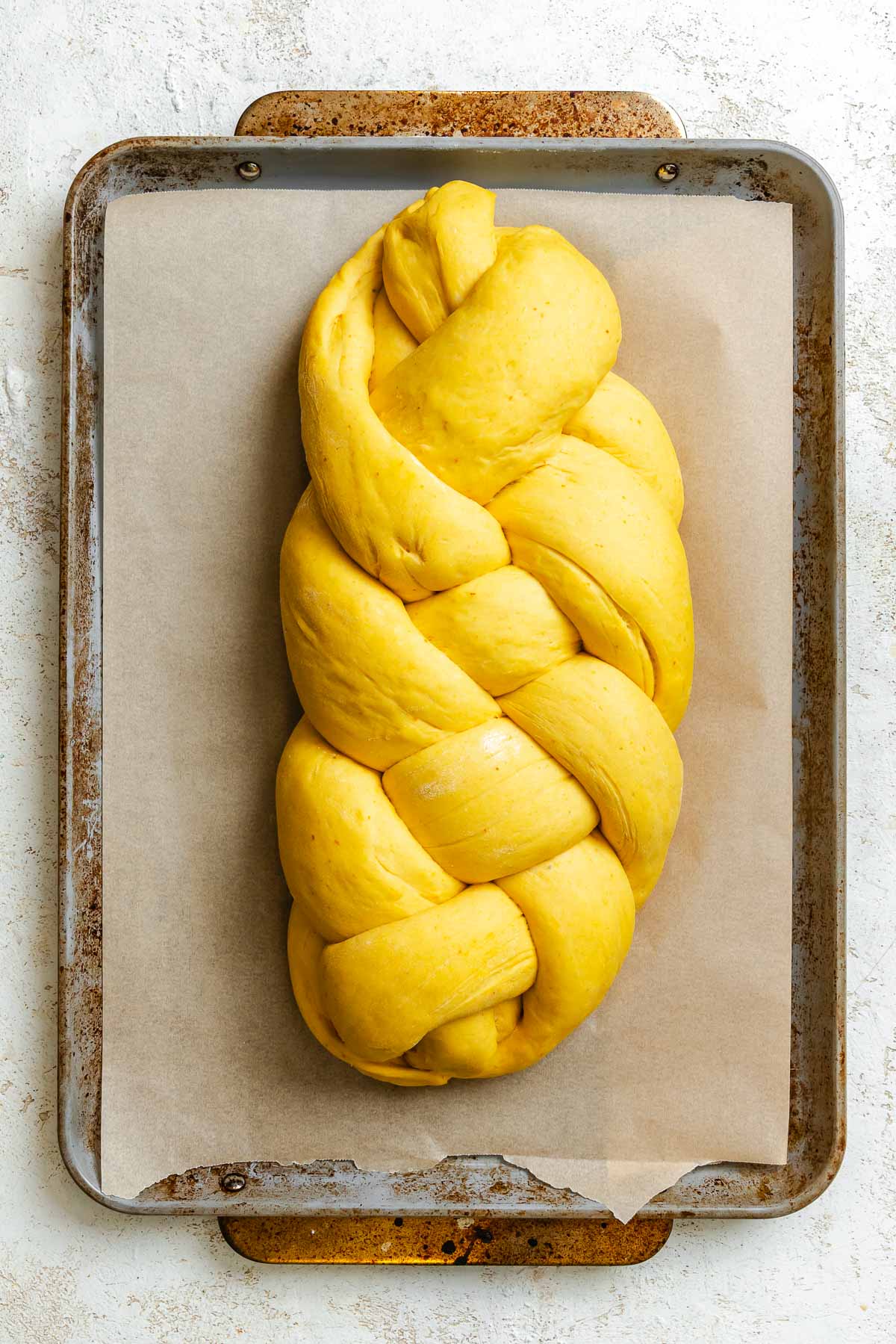 Process shot showing pre-baked vegan challah on baking sheet.