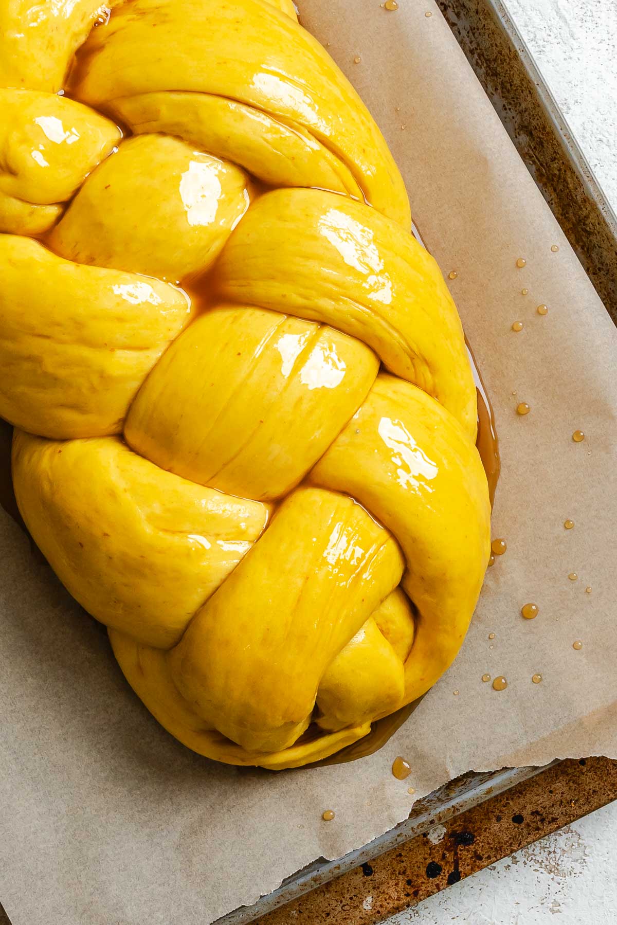 Process shot showing pre-baked vegan challah on baking sheet.