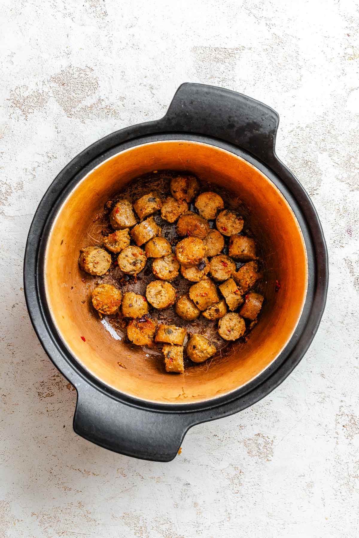 Process shot showing vegan sausage cooking in pot.