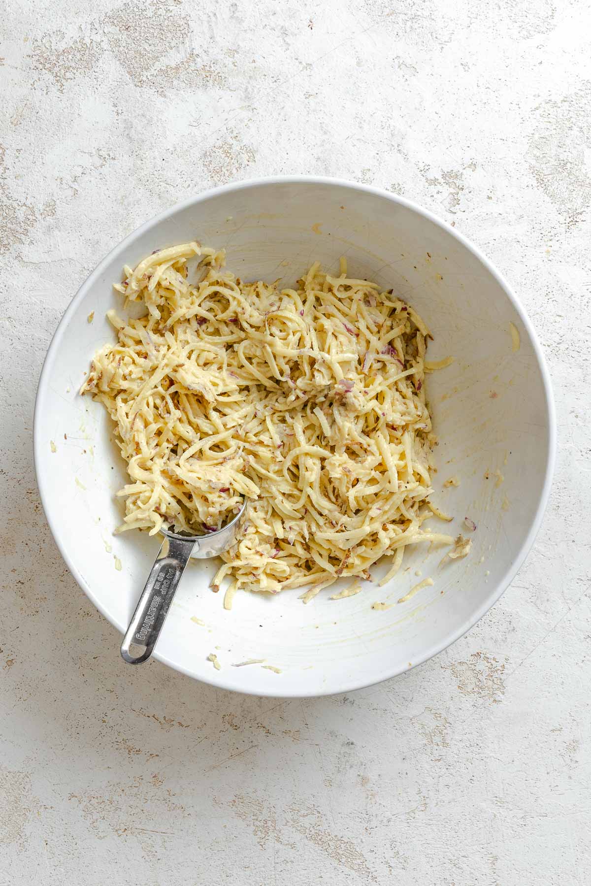 Process shot showing scooping potato mixture from bowl.