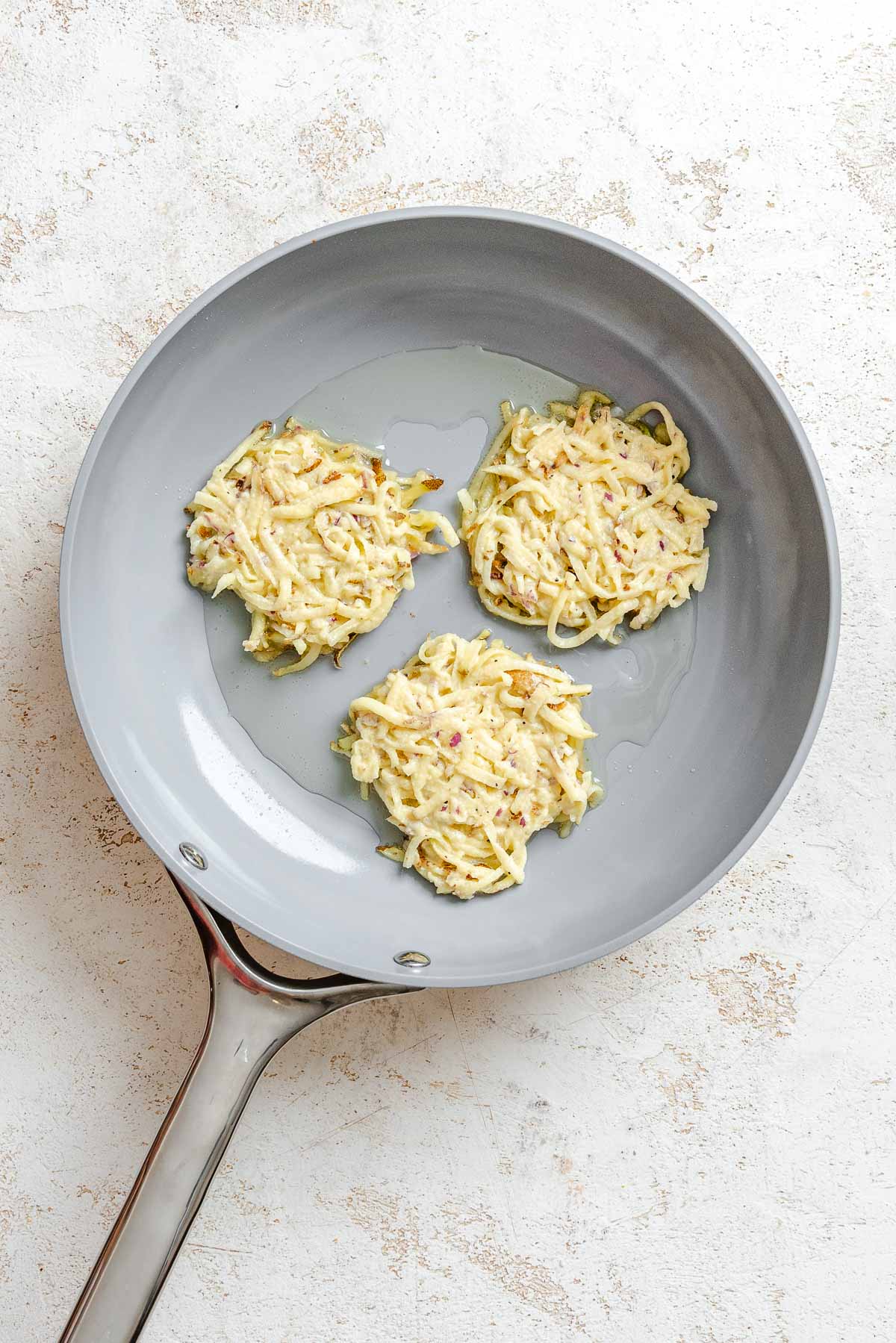 Process shot showing added potato mixture to a pan.