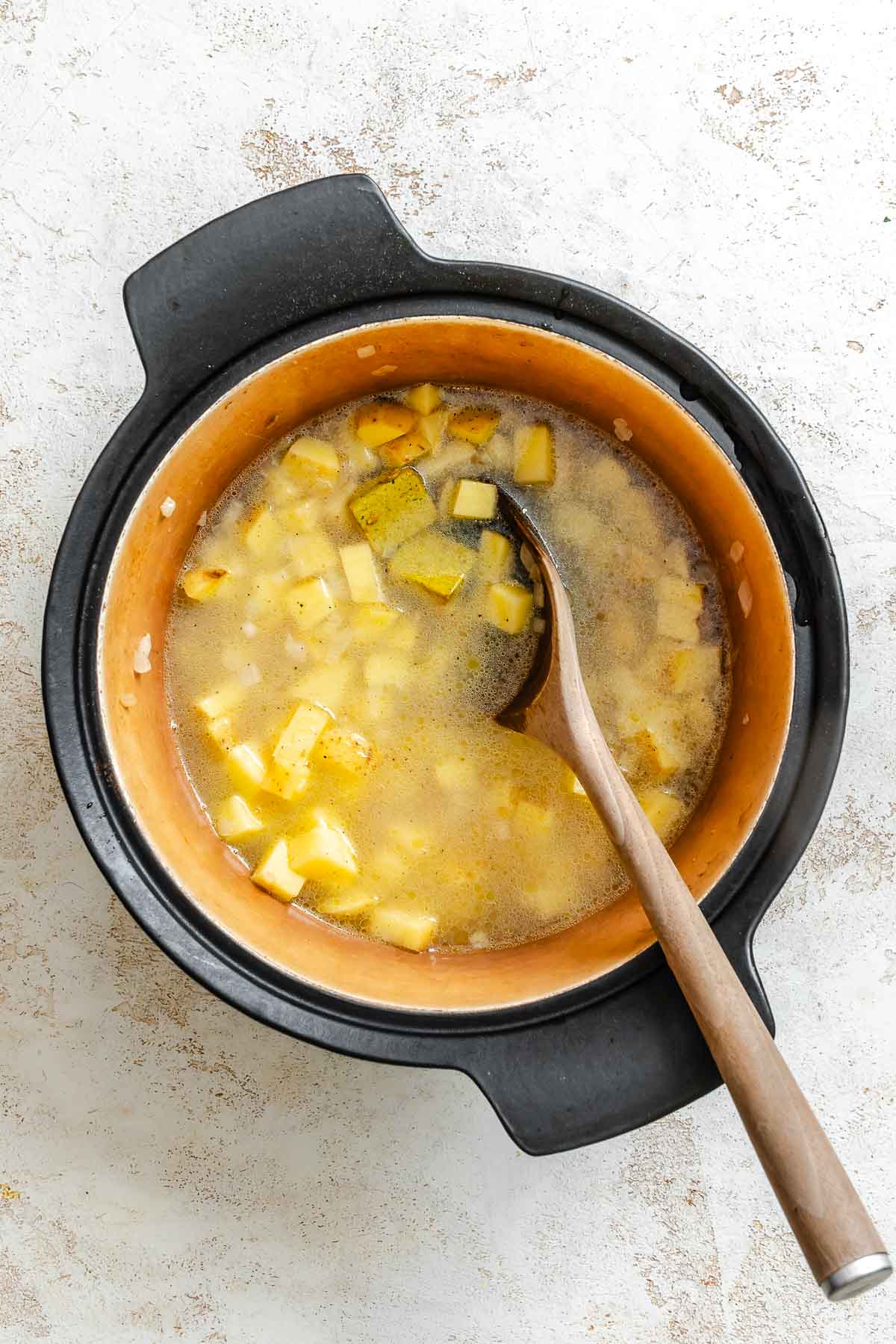 Process shot showing stirring ingredients in pot.