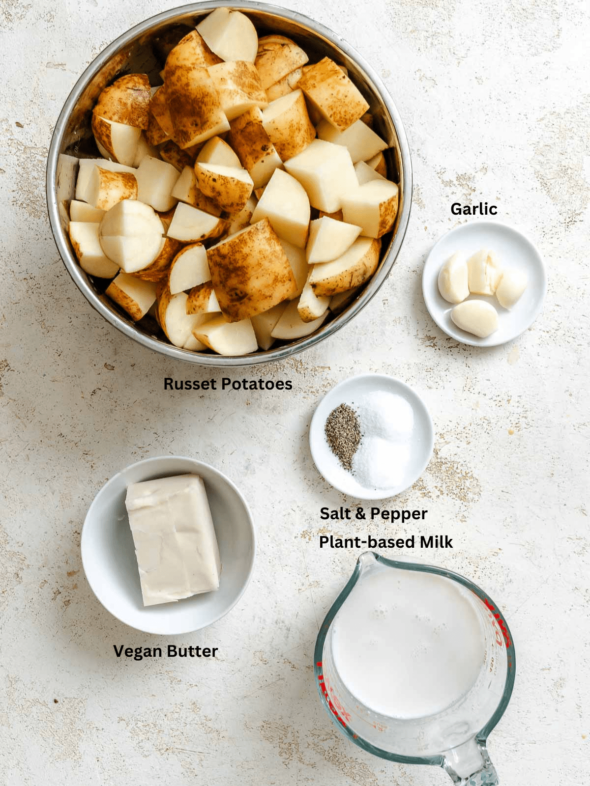 Ingredients for Make the BEST Garlic Mashed Potatoes [+ Mix-Ins] measured out on a white surface.